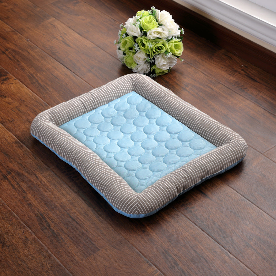 Blue quilted pet bed with gray striped bolstered edge placed on a wooden floor